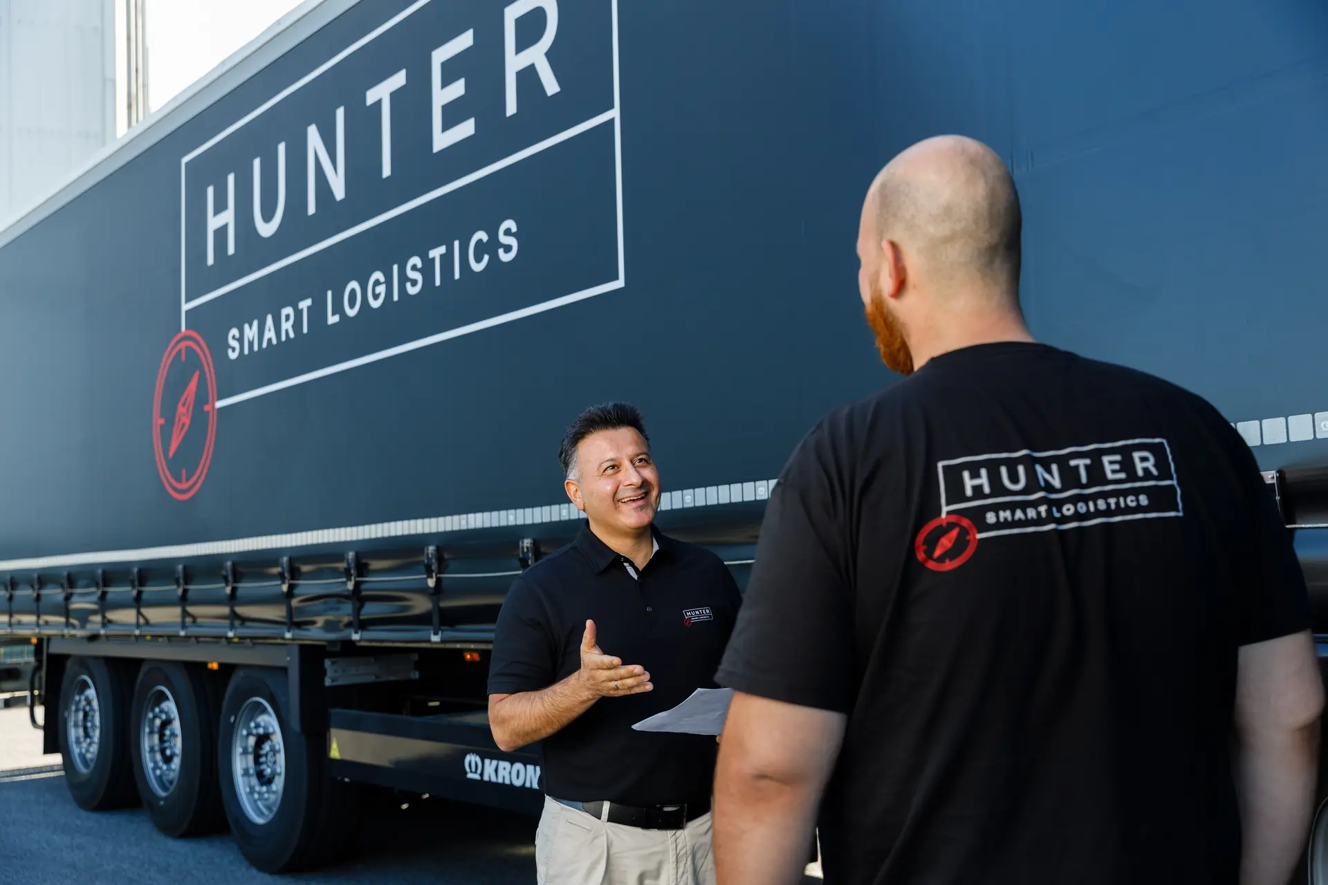 Ansprechpartner von HUNTER Logistics im Gespräch mit einem Fahrer vor einem Sattelauflieger